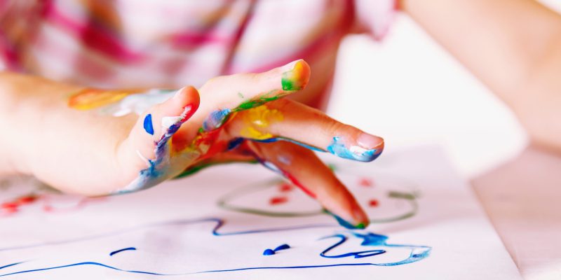 Close up young girl painting with colorful hands. Art,  creativity and painting concept. Horizontal image.